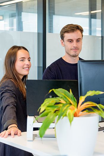 Twee collega’s bekijken samen een scherm en werken aan online klantreistraject